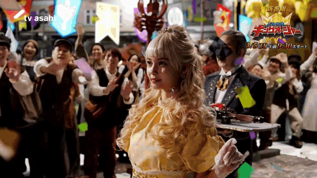 a woman in a yellow dress stands in front of a crowd with a tv asahi logo