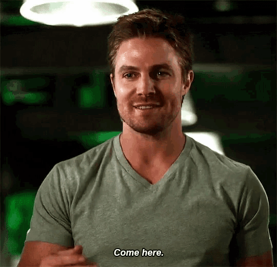 a man in a gray shirt is smiling and saying come here