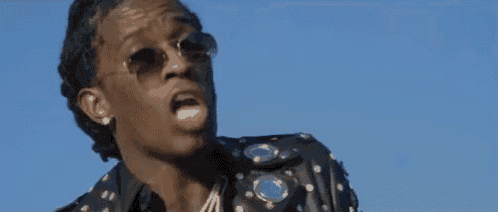 a man wearing sunglasses and a black shirt is making a funny face in front of a blue sky .