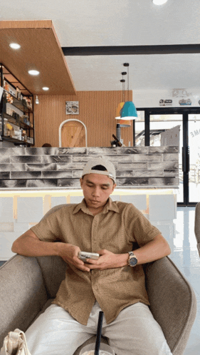 a man sits in a chair looking at his cell phone