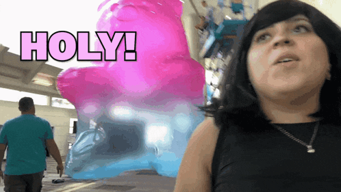 a woman stands in front of a giant gummy bear with the words holy written on it
