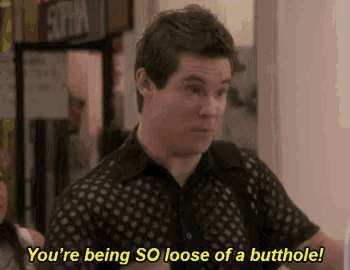 a man in a black shirt is standing in a hallway and talking to someone .