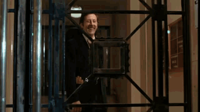 a man in a suit and tie is waving through a fence