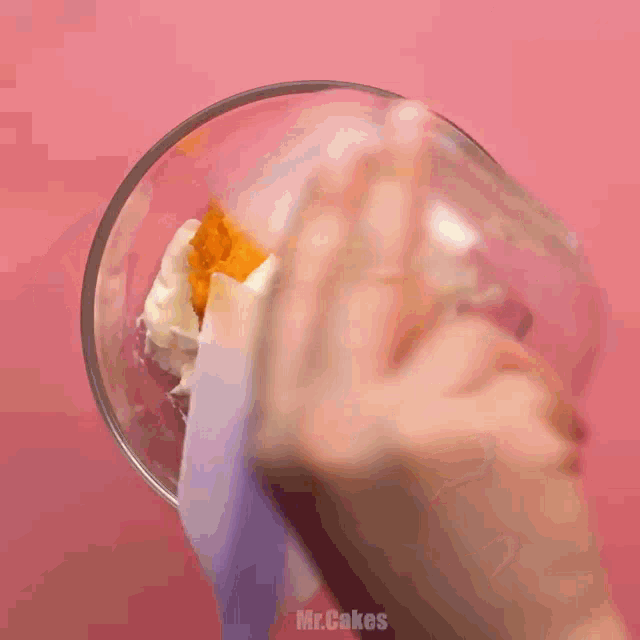 a person is using a spatula to mix ingredients in a glass bowl with the words mr.cakes written on the bottom
