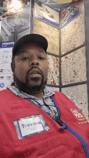 a man wearing a red vest and name tag that says travaris