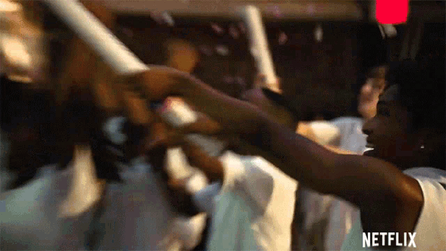 a woman in a white dress is dancing in a crowd with a netflix logo in the corner .