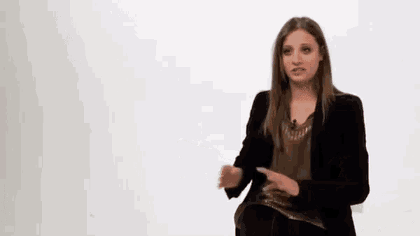 a woman in a black jacket stands in front of a white board that says twitter