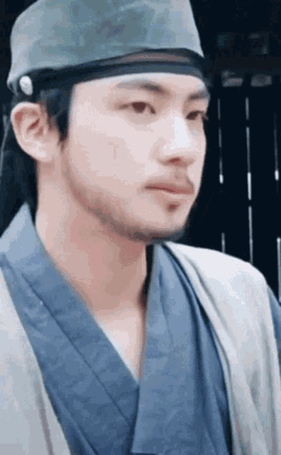 a close up of a man with a beard wearing a hat and kimono .