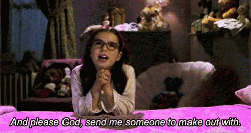 a little girl with glasses is sitting on a bed praying to god .