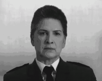 a woman in a suit and tie is standing in front of a white wall .