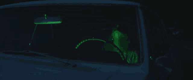 a person driving a car with a green light on the windshield