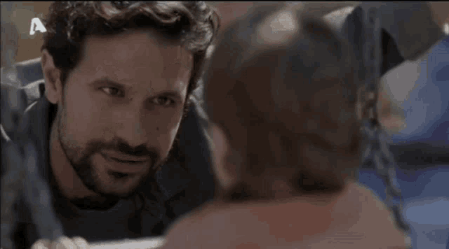 a man with a beard is looking at another man 's face