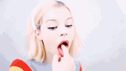 a close up of a woman licking her lips with her tongue out .