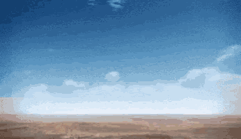 a desert with a blue sky and white clouds