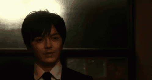 a man in a suit and tie is looking at the camera .
