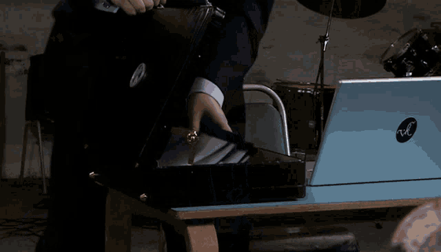 a man is opening a briefcase next to a laptop that says hp on it