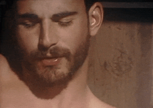a close up of a man 's face with his eyes closed and a beard