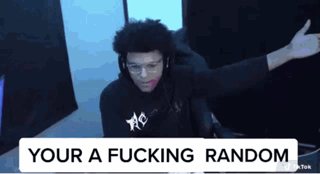 a man is sitting in front of a computer with his arms outstretched and a sign that says `` your a fucking random ''