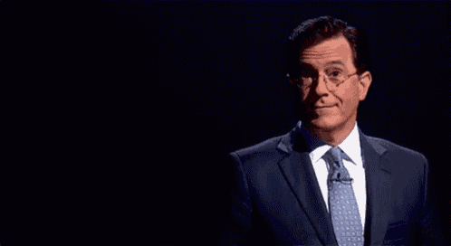 a man in a suit and tie is standing in front of a black background that says thumb in butt