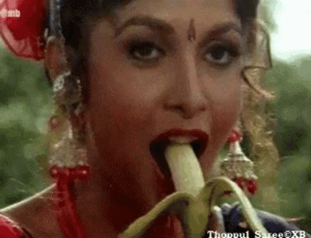 a woman in a red dress is eating a banana .