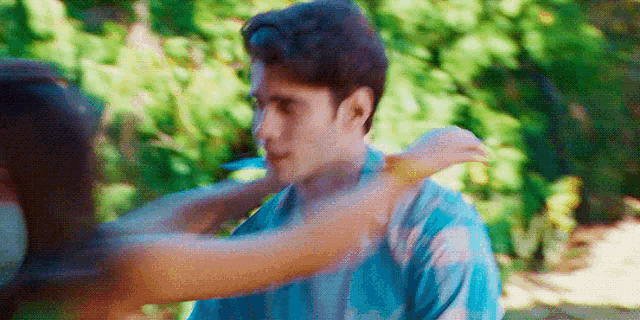 a woman is holding a man 's neck in a park .