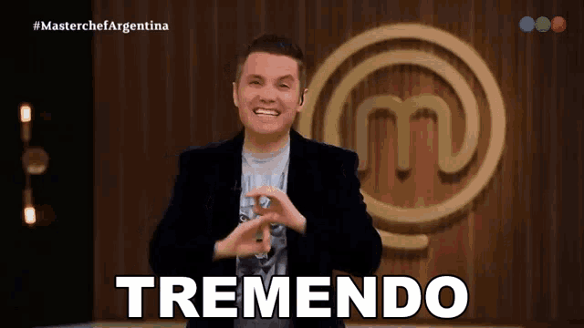 a man stands in front of a masterchef argentina logo and says tremendo