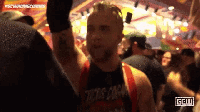 a man stands in a crowd wearing a shirt that says " tricks coach "