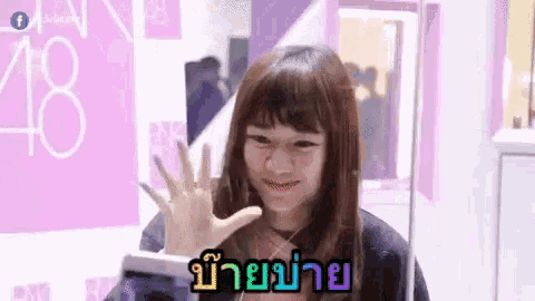 a girl is waving her hand in front of a pink wall and a sign that says 48 .
