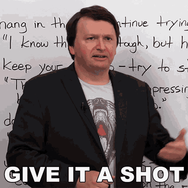 a man stands in front of a white board with the words " give it a shot " written on it