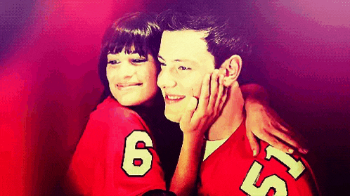 a man and a woman are posing for a picture together . the man is wearing a red jersey with the number 6 on it .