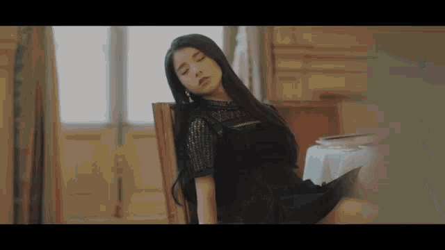 a woman in a black dress is sitting in a chair .