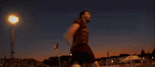 a man in a soccer uniform is running on a field at night