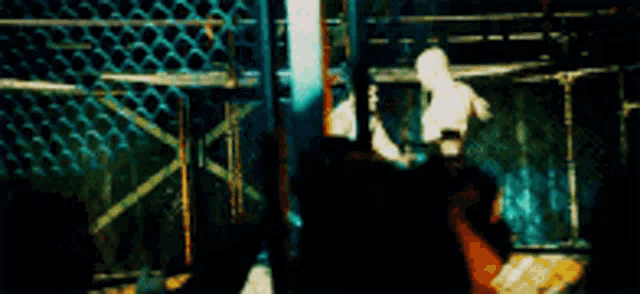 a blurry picture of a person in a dark room with a chain link fence in the background