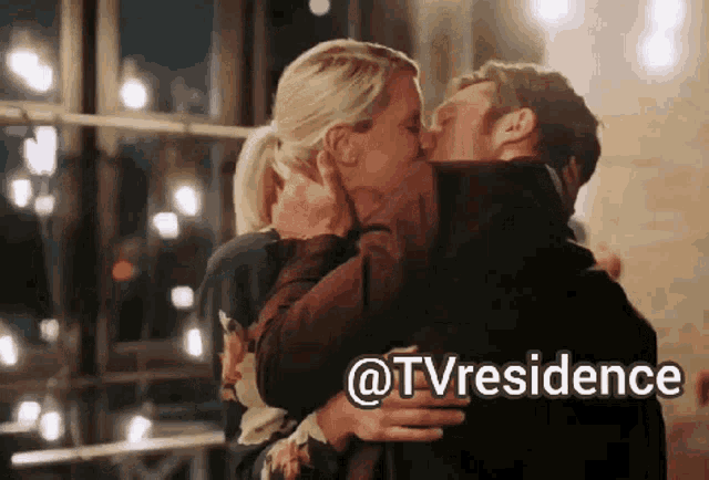 a man and a woman kissing in front of a window with the words @tvresidence written below them