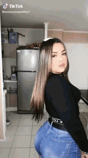 a woman is standing in front of a refrigerator in a kitchen and has tiktok written on the bottom right