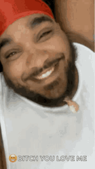 a man with a beard wearing a red headband and a white shirt is smiling and says bitch you love me