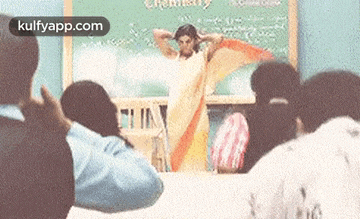a woman in a saree is standing in front of a classroom full of people .