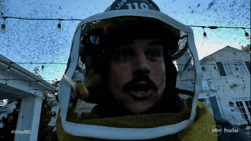a man wearing a helmet with the number 110 on it stands in front of a house