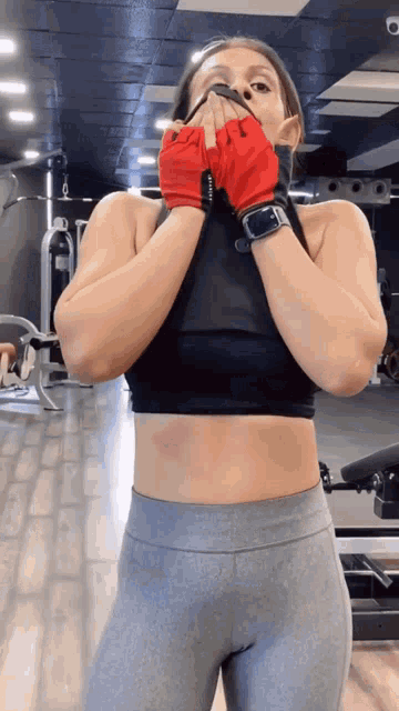 a woman in a gym wearing a black top and grey pants