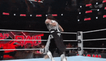 two wrestlers are wrestling in a ring with the word raw written on the wall behind them
