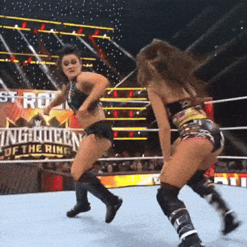 two women are wrestling in a ring with a sign behind them that says ' king queen of the ring '