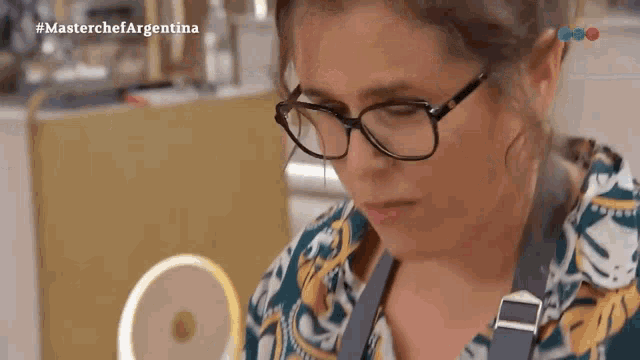 a woman wearing glasses is looking at something in front of a mirror with the words masterchef argentina on the bottom