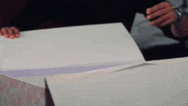a person is opening a white box with a purple ribbon on it