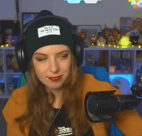a woman wearing headphones and a green beanie is sitting in front of a microphone