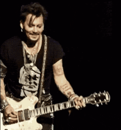 a man in a black shirt is playing a guitar on a stage .