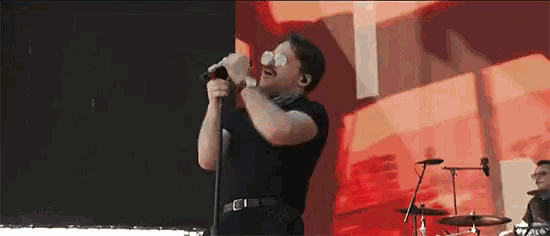a man singing into a microphone wearing sunglasses