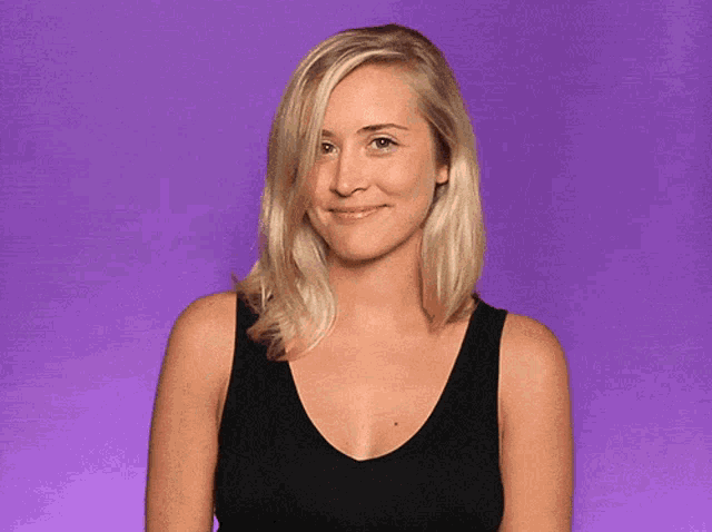 a woman in a black tank top is smiling and waving