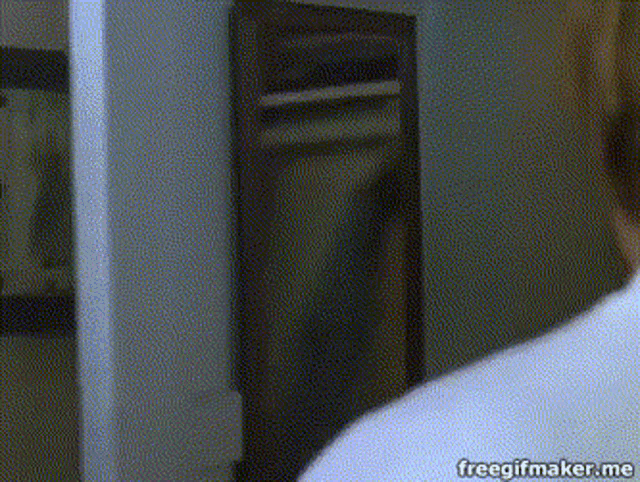 a man in a white shirt is looking at himself in the mirror .