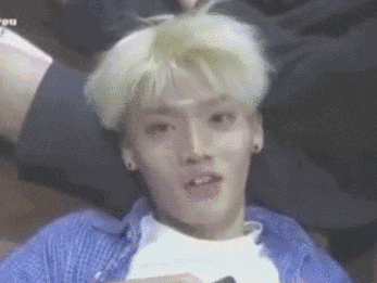 a young man with blonde hair is laying on the floor with his mouth open .