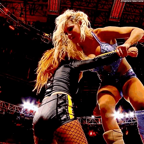 two women are wrestling in a ring and one is wearing a black top